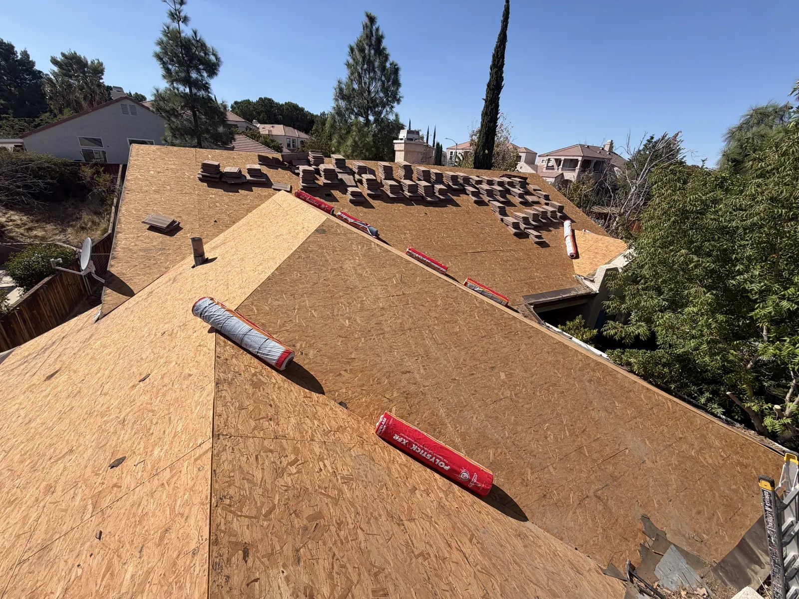 Roof covered in fresh OSB decking with underlayment rolls