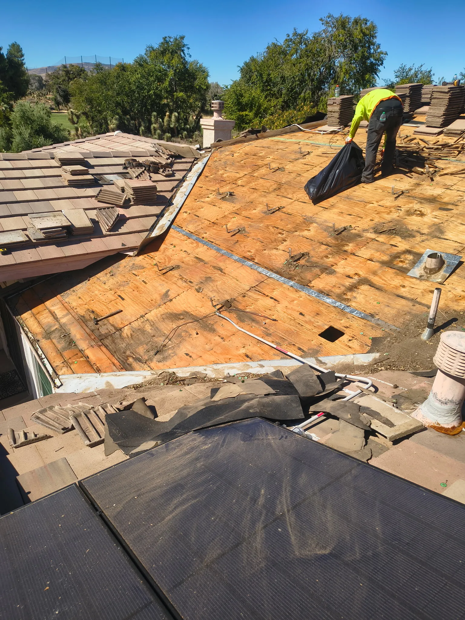 Looking down a stripped slope: bare deck above, the old tile still on below