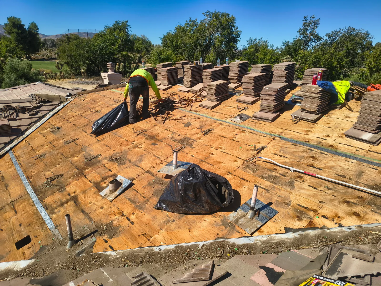 Crew stripping a tile roof to the deck, tile stacked in rows