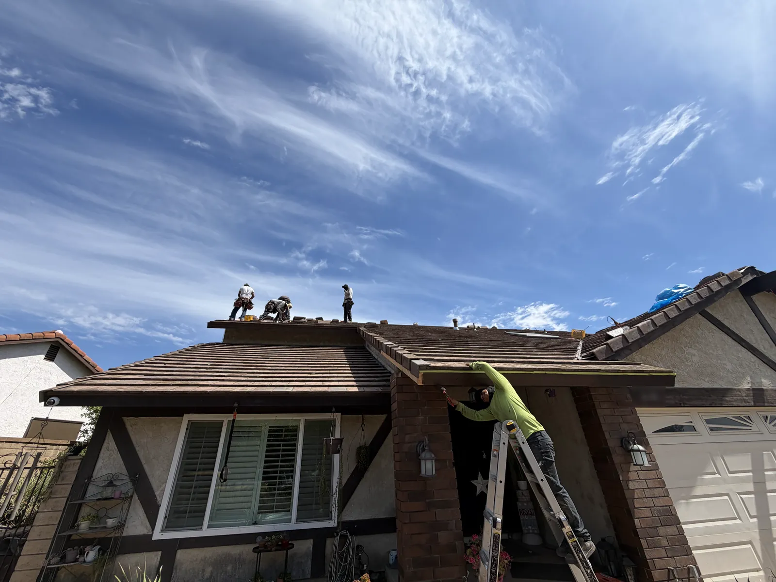 Superior crew on a two-story roof, one on a ladder at the eave
